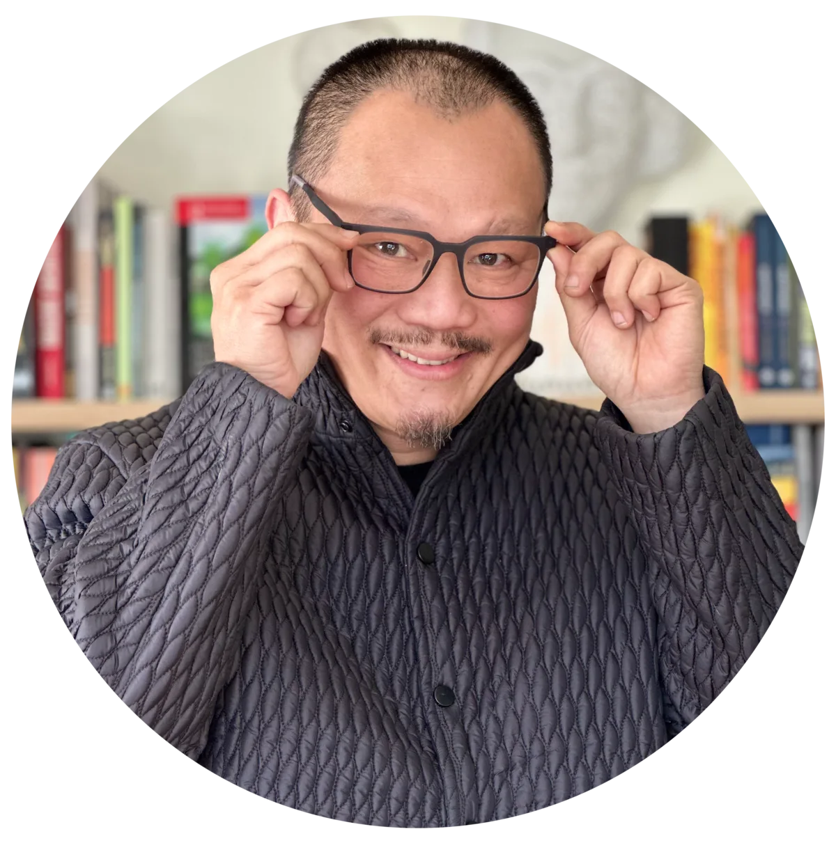 Frven Lim standing in a library surrounded by leadership and wellbeing books